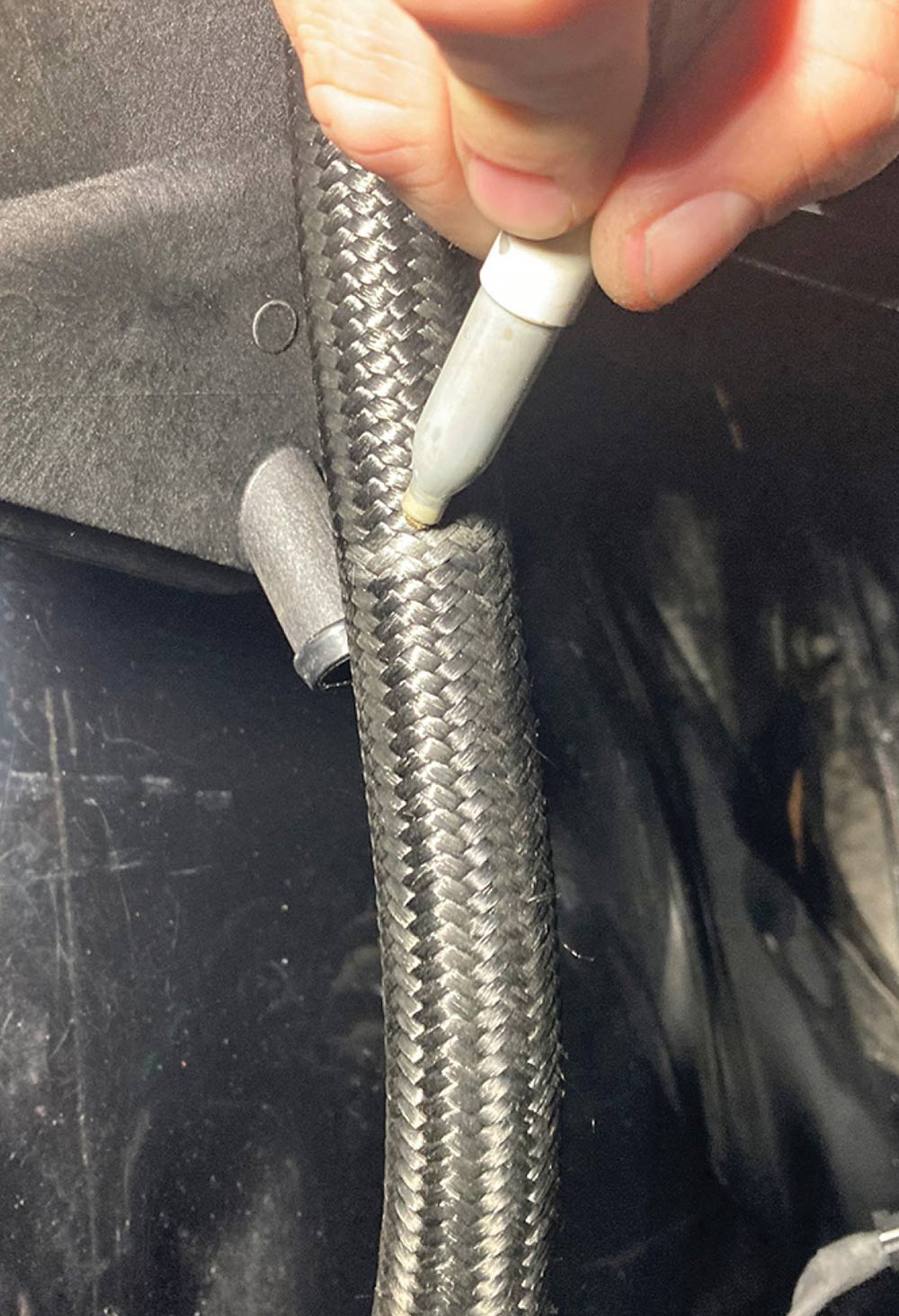 Marking a braided hose with a white paint pen.