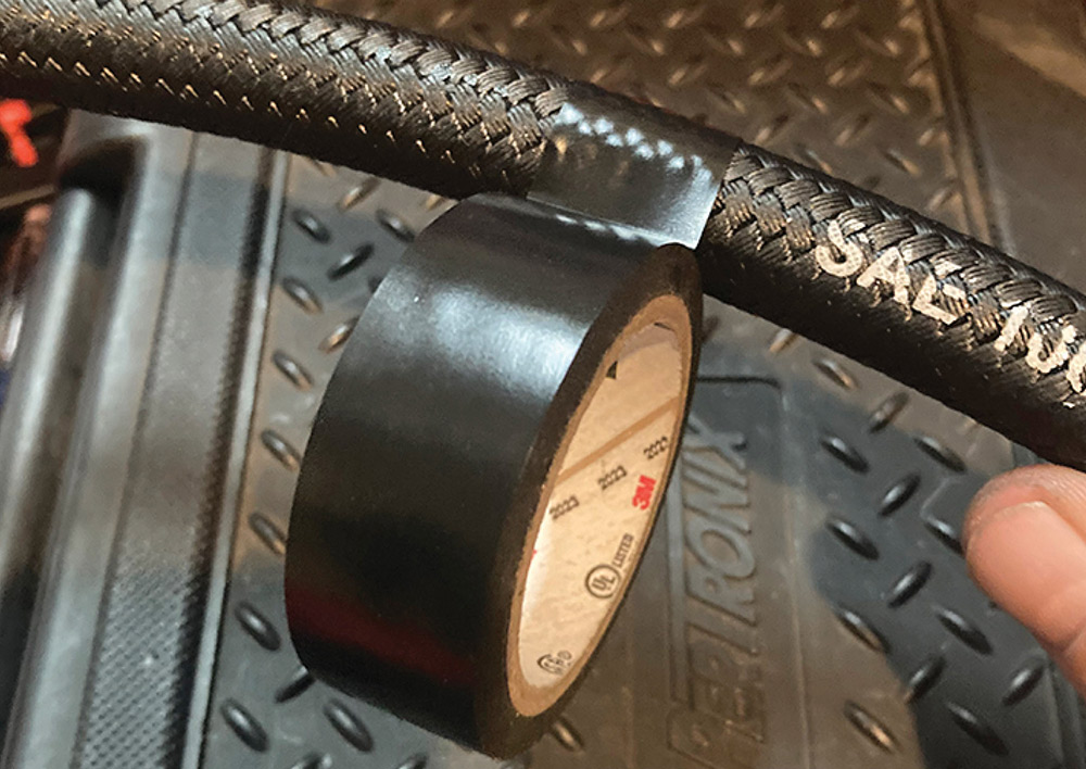 Applying electrical tape to a braided hose before cutting.
