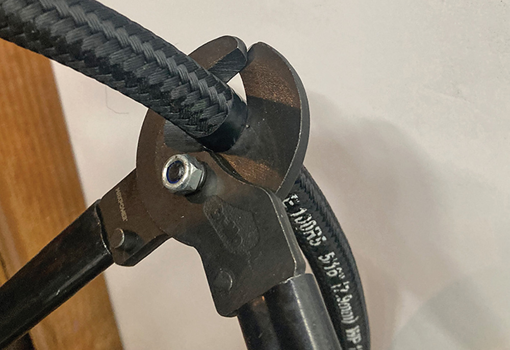 Cable cutters being used to cut a braided hose.