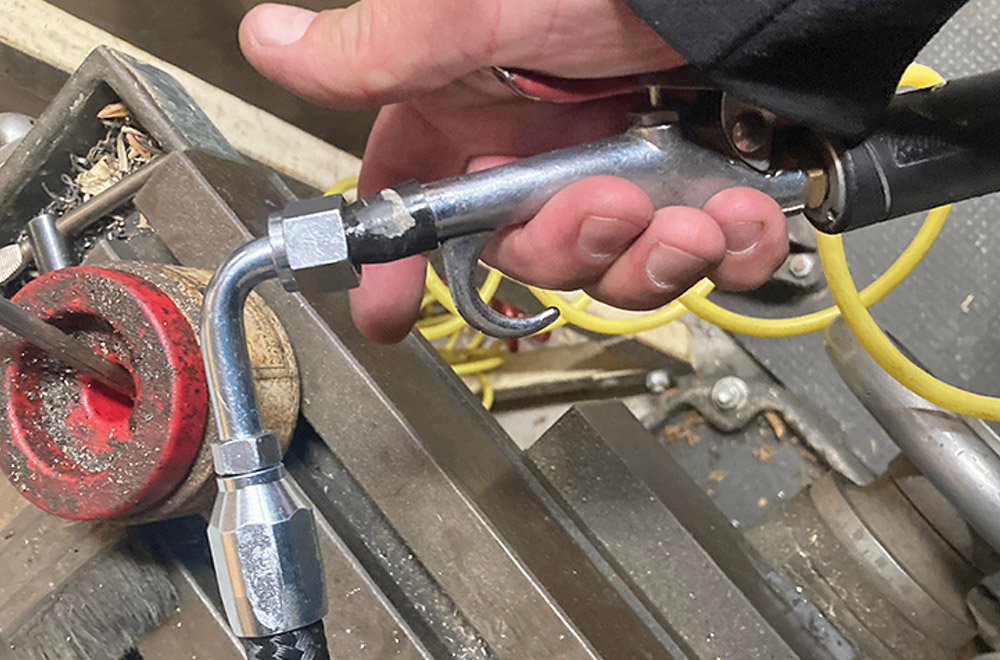 Compressed air nozzle cleaning out a new hose assembly.