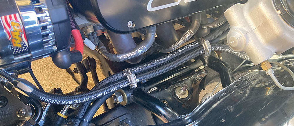 Braided hydraulic hoses secured with hose clamps and zip ties.