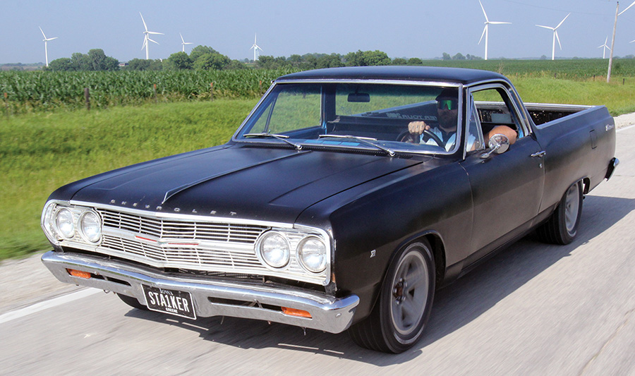 Black El Camino "Stalker" driving on a rural road past wind turbines.