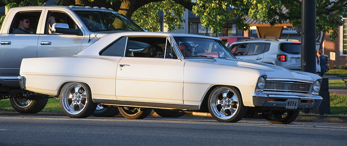 White 1966 Nova cruising at sunset