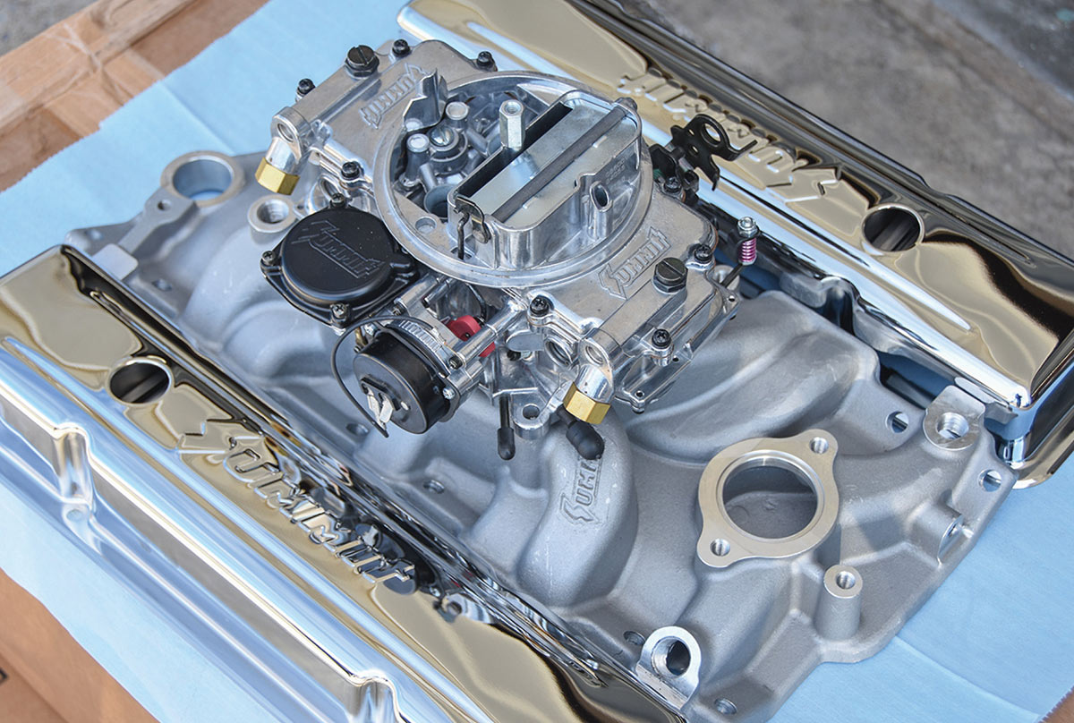 Aluminum intake manifold with four-barrel carburetor and valve covers.