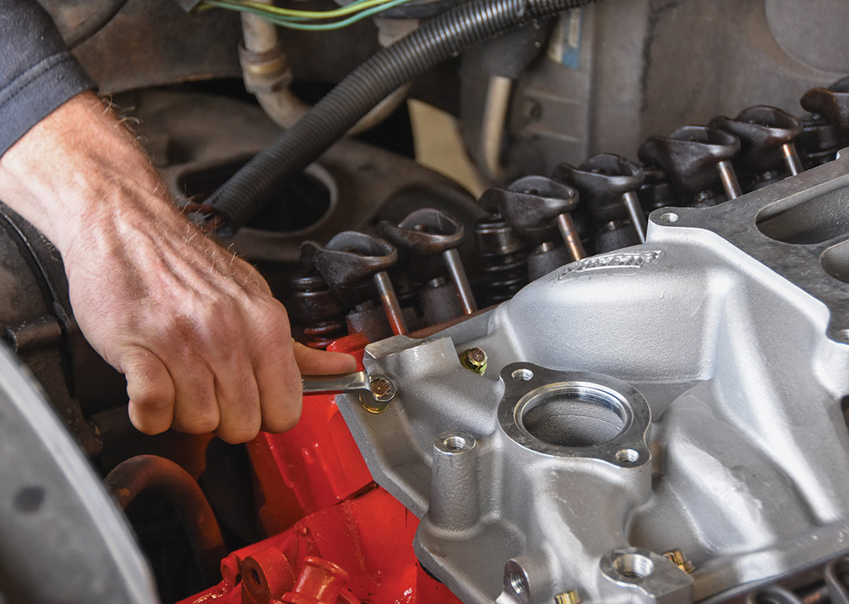 Tightening zinc-plated intake manifold bolts with a wrench.