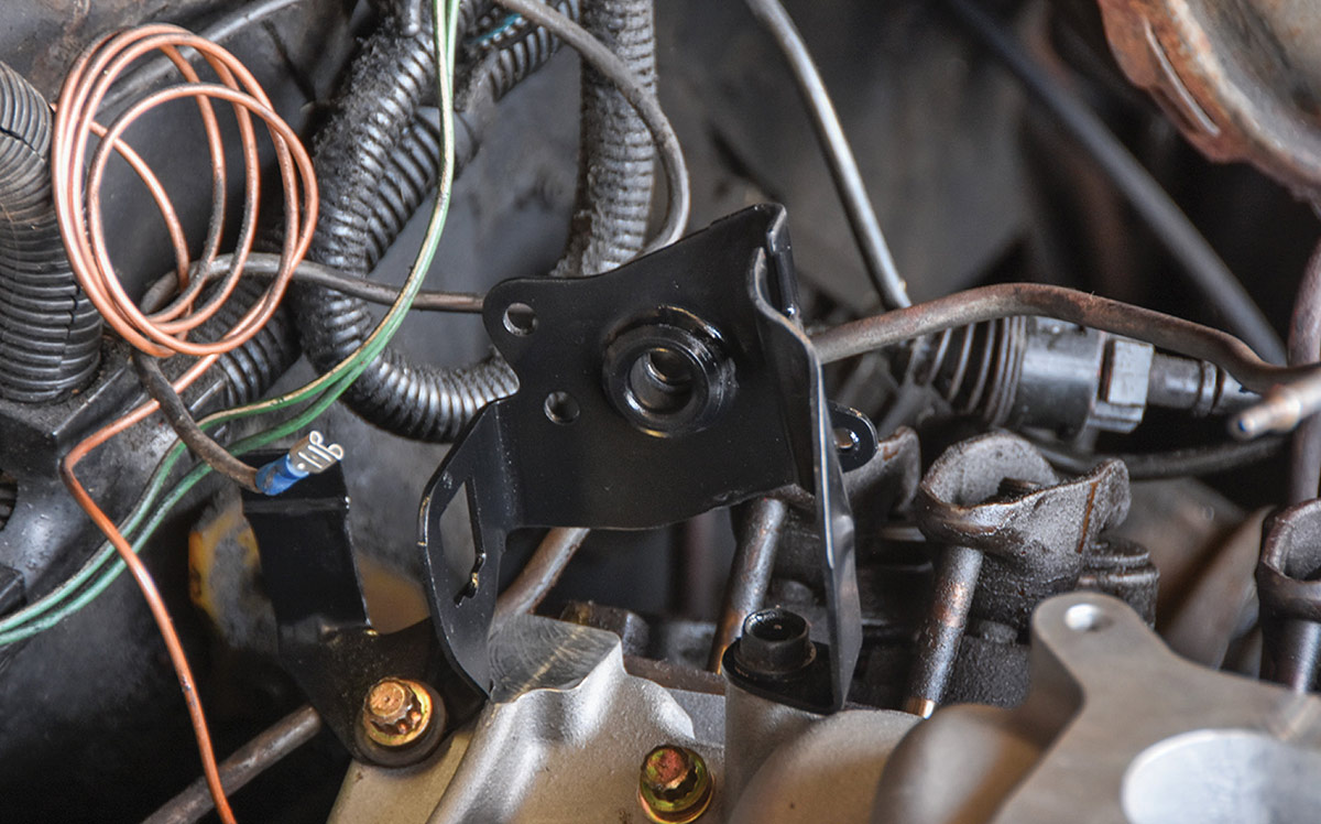 Original throttle cable bracket modified for new intake.