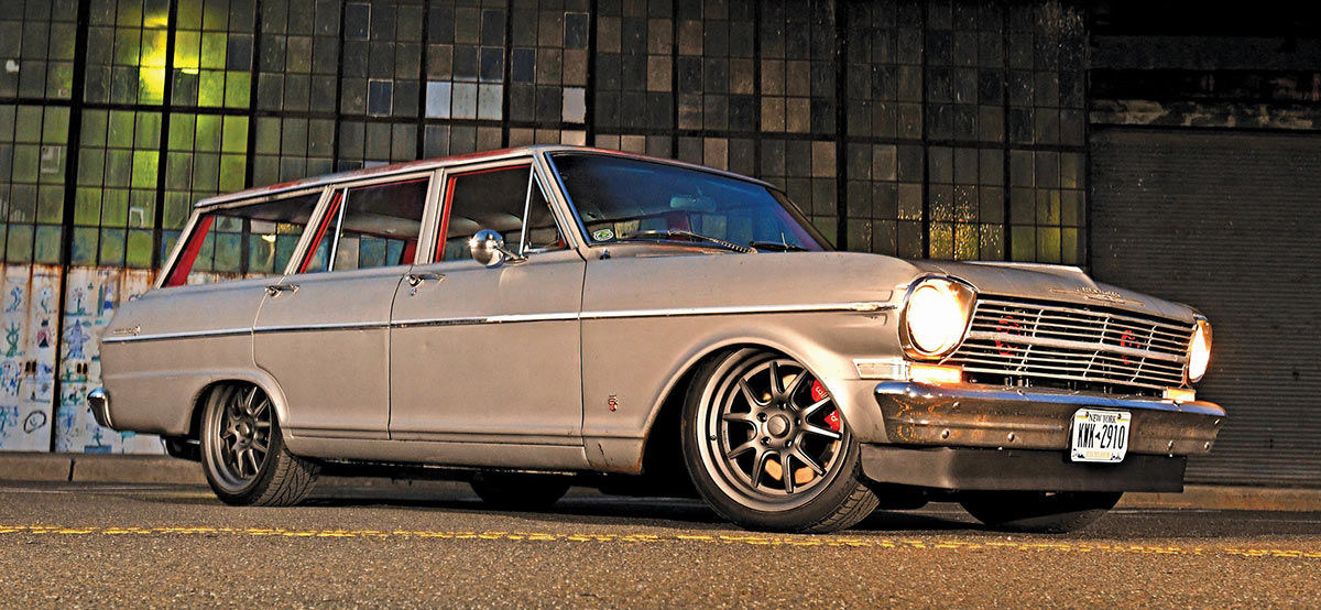 Grey Nova wagon parked in front of an industrial warehouse building.