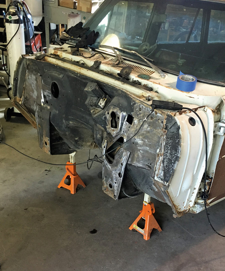 Bare car firewall supported by orange jack stands.