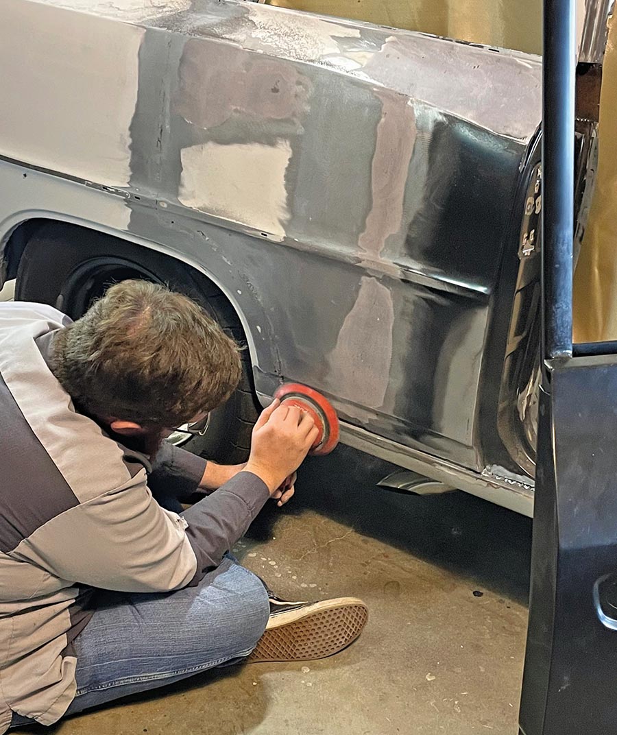 Technician using a circular sander on the rear quarter.