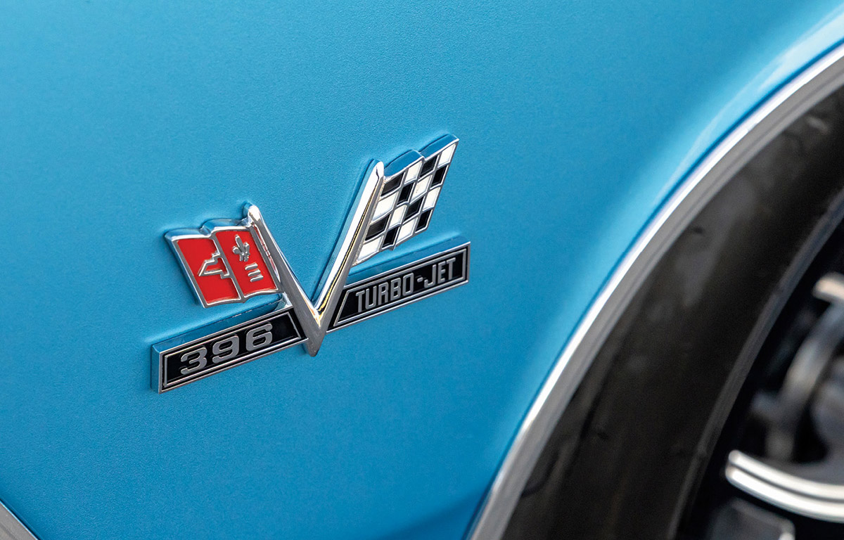 Close-up of a chrome 396 Turbo-Jet crossed-flags emblem on a blue car fender.