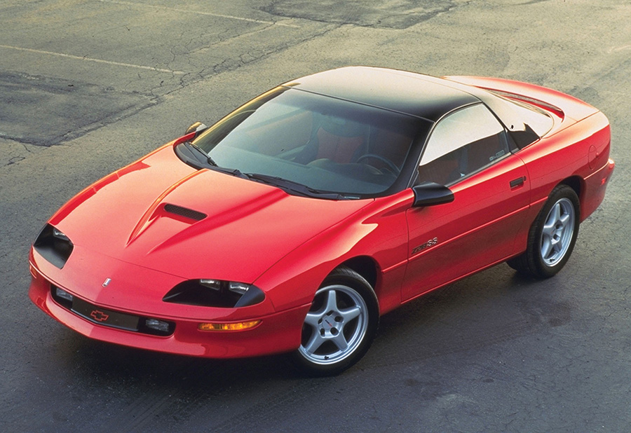 Red fourth-generation Camaro Z28 on a roadway.