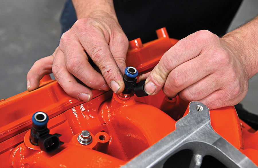 Fitting GM fuel injectors into the intake manifold.