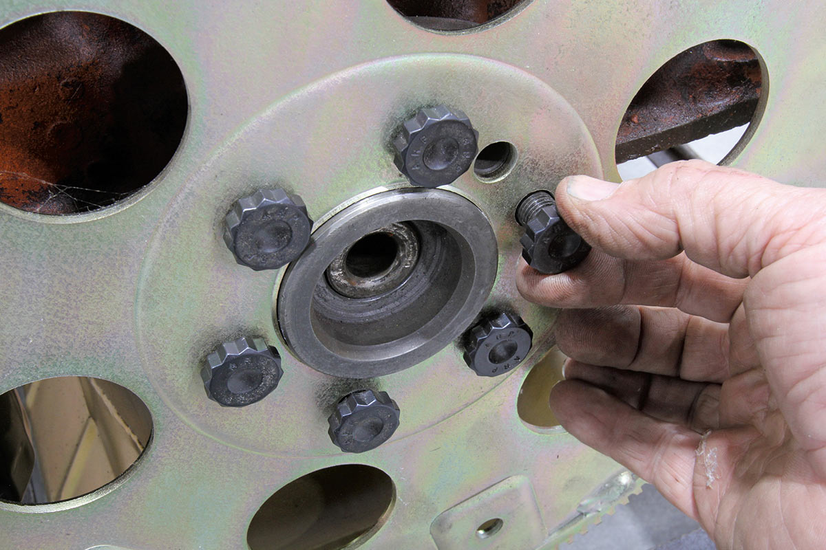 Hand installing high-strength flexplate mounting bolts.