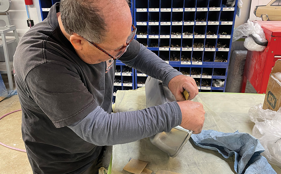 Hand-sanding a valve cover for custom paint preparation.
