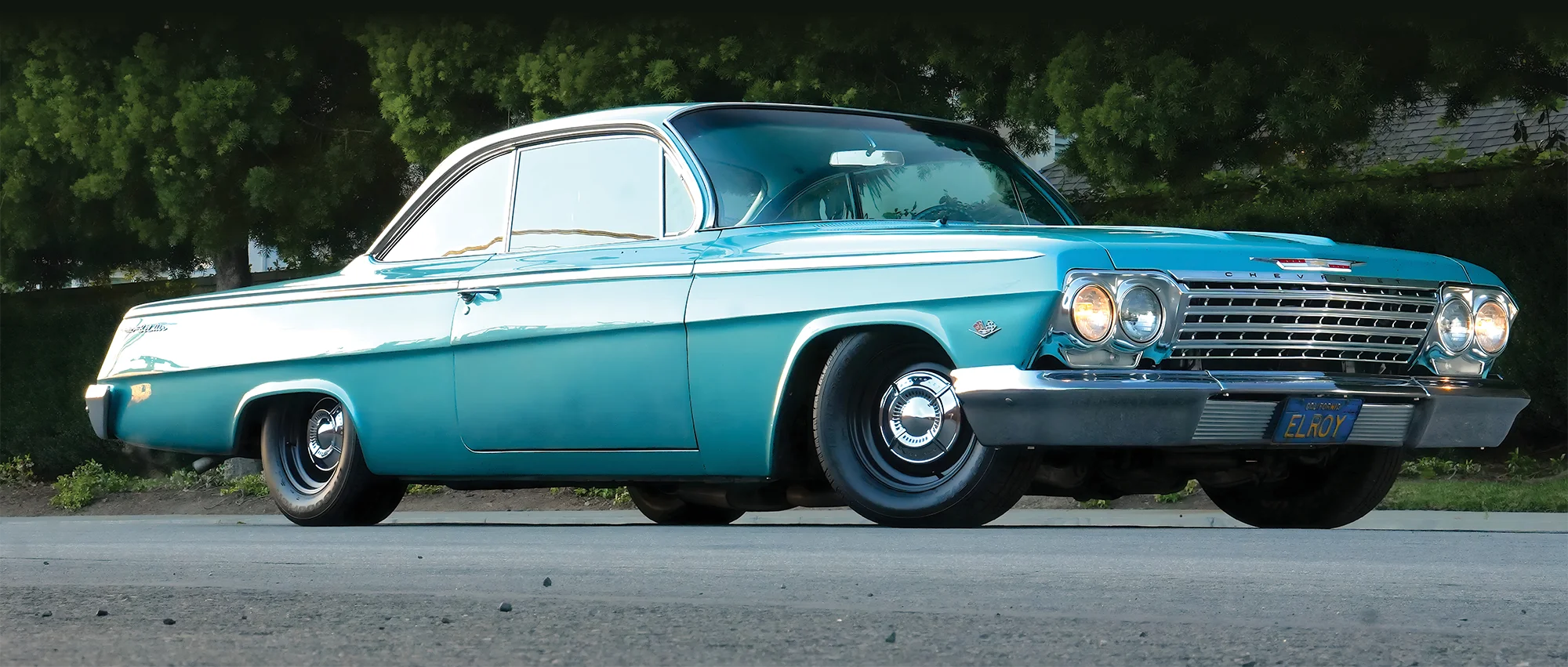 Low-angle front three-quarter view of a turquoise 1962 Chevy bubbletop.