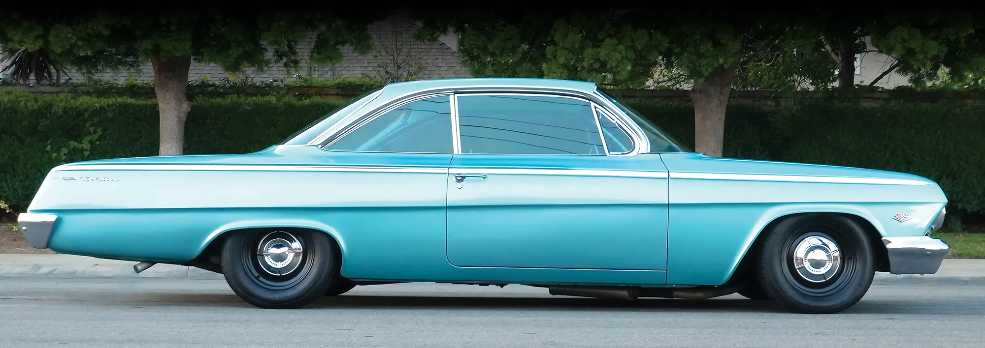rofile view of a lowered turquoise 1962 Chevy Bel Air bubbletop.