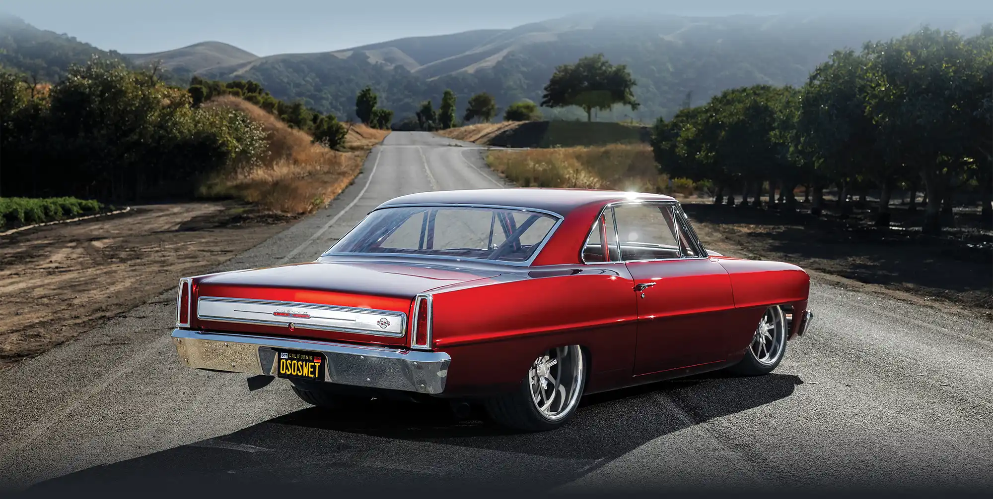 Rear view of a red 1966 Nova SS on a road.